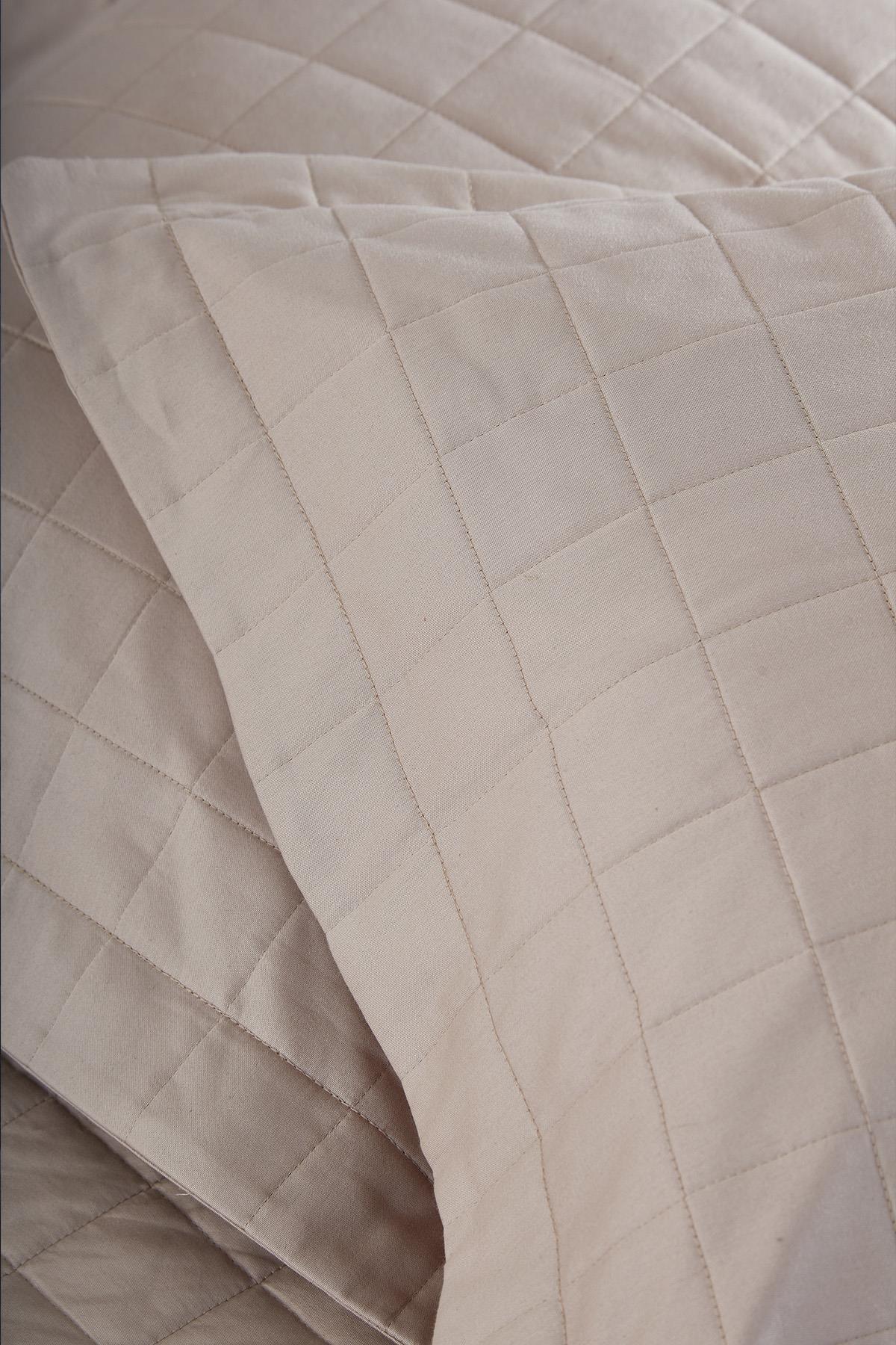 Kapitoneli çift kişilik bej yatak örtüsü ve yastık kılıfı yakın çekim