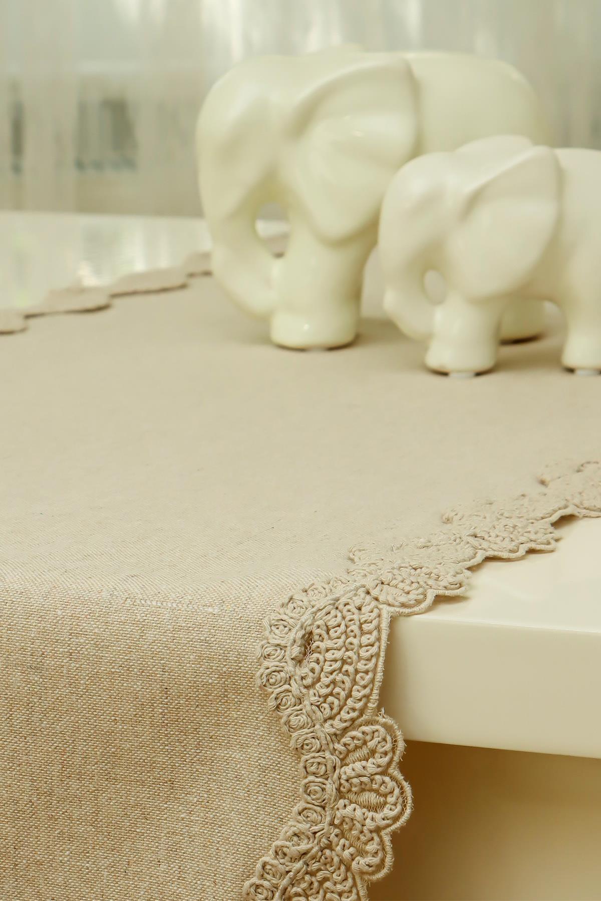 Dantel kenarlı krem renk masa örtüsü üstünde porselen fil dekorlar
